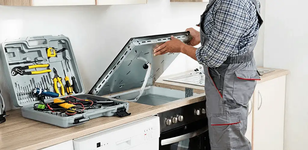 Handyman repairing a cooktop and checking wiring connections in Birmingham, AL