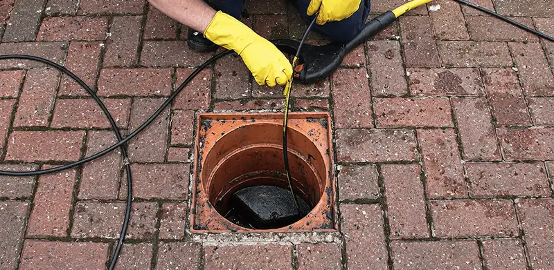 Drain cleaning technician using a drain snake to clear a clogged drain in Birmingham, AL