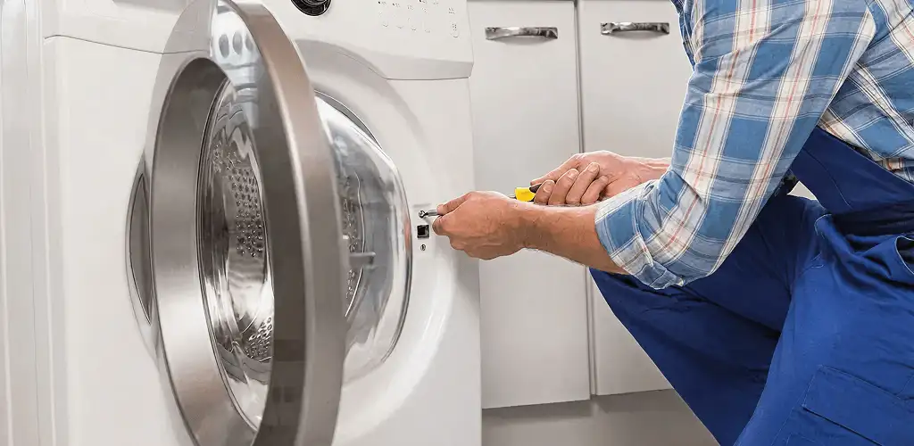 Handyman repairing a clothes dryer and checking electrical connections in Birmingham, AL