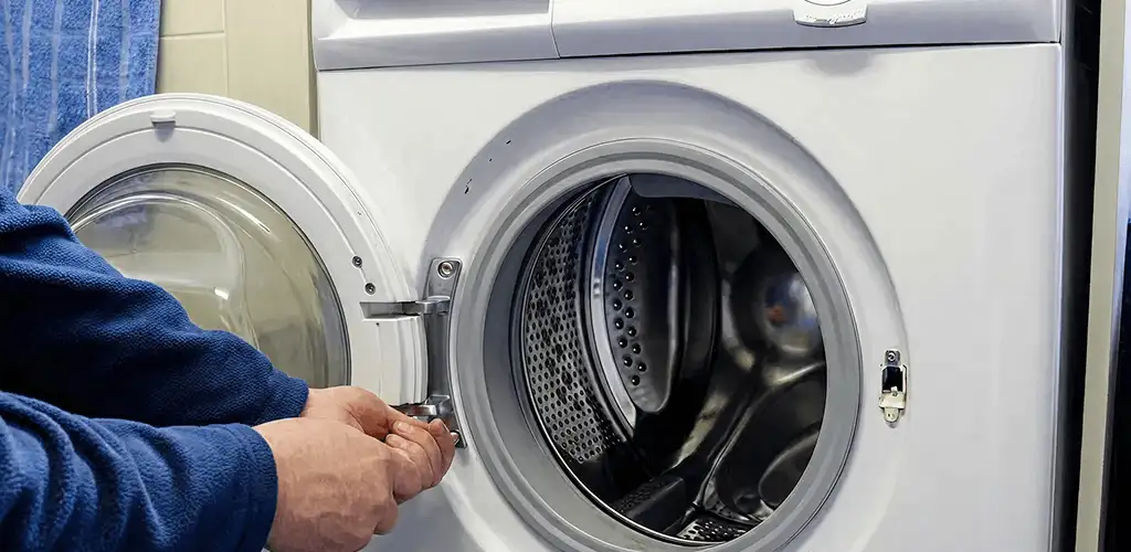 Washing machine repair handyman checking a front-load washer door and latch in Birmingham, AL