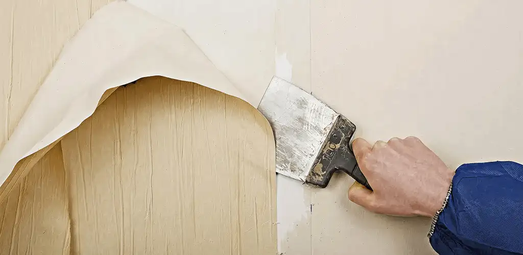 Handyman removing wallpaper with a scraper for wall preparation in Birmingham, AL