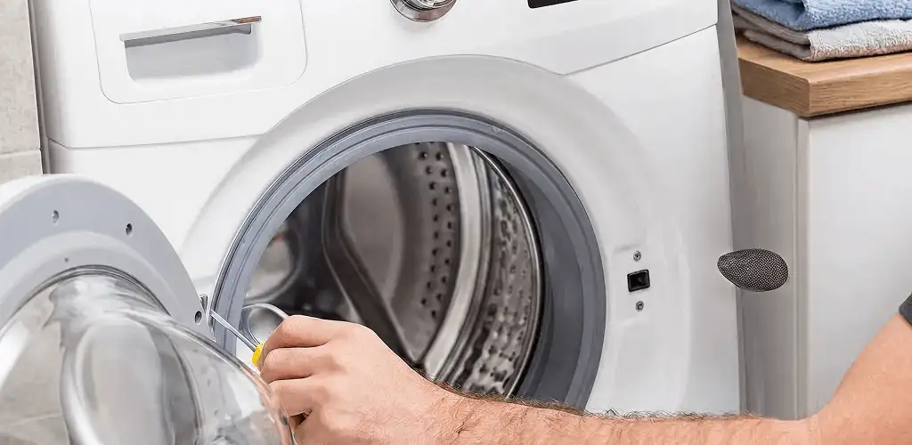Handyman repairing a front-load washing machine and inspecting the drum in Birmingham, AL
