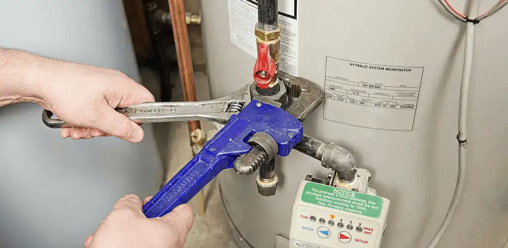 Water heater repair technician tightening the shutoff valve and supply line in Birmingham, AL